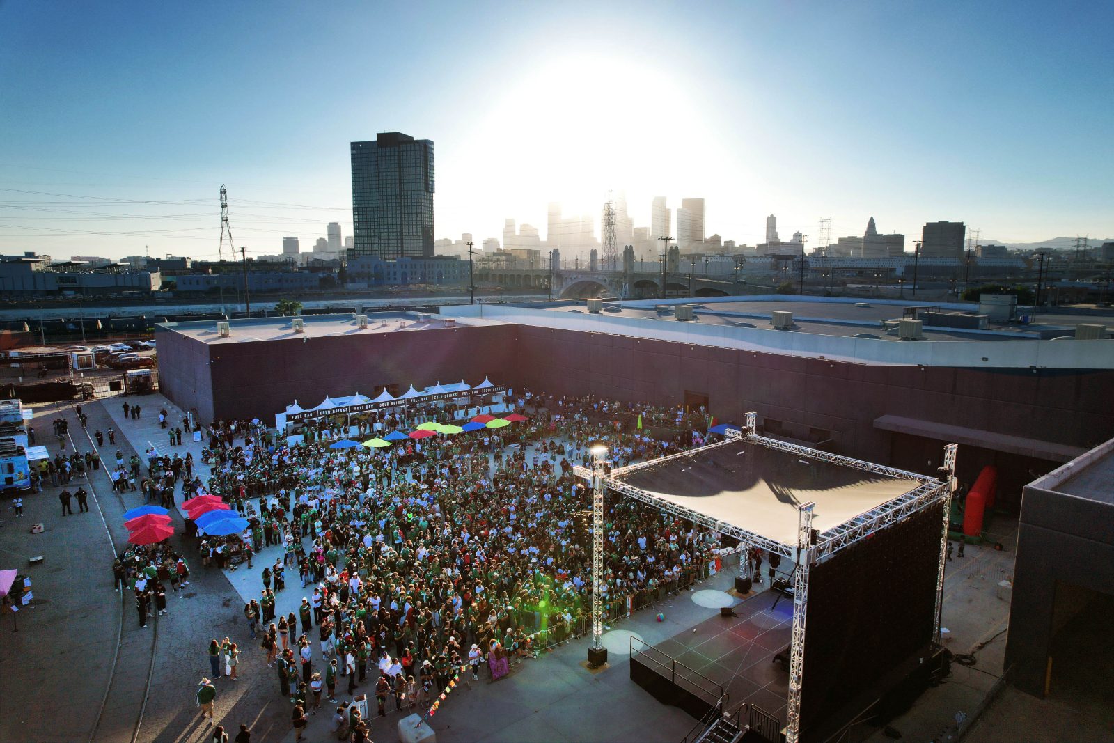 Aerial view of the fan hub crowd and main stage with the downtown skyline behind
