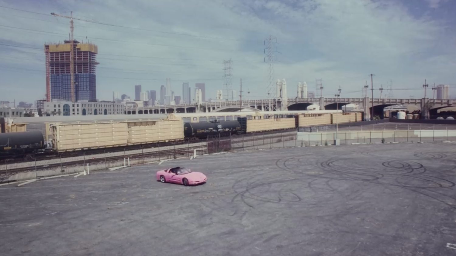 Pink Corvette in a back lot with the LA skyline behind