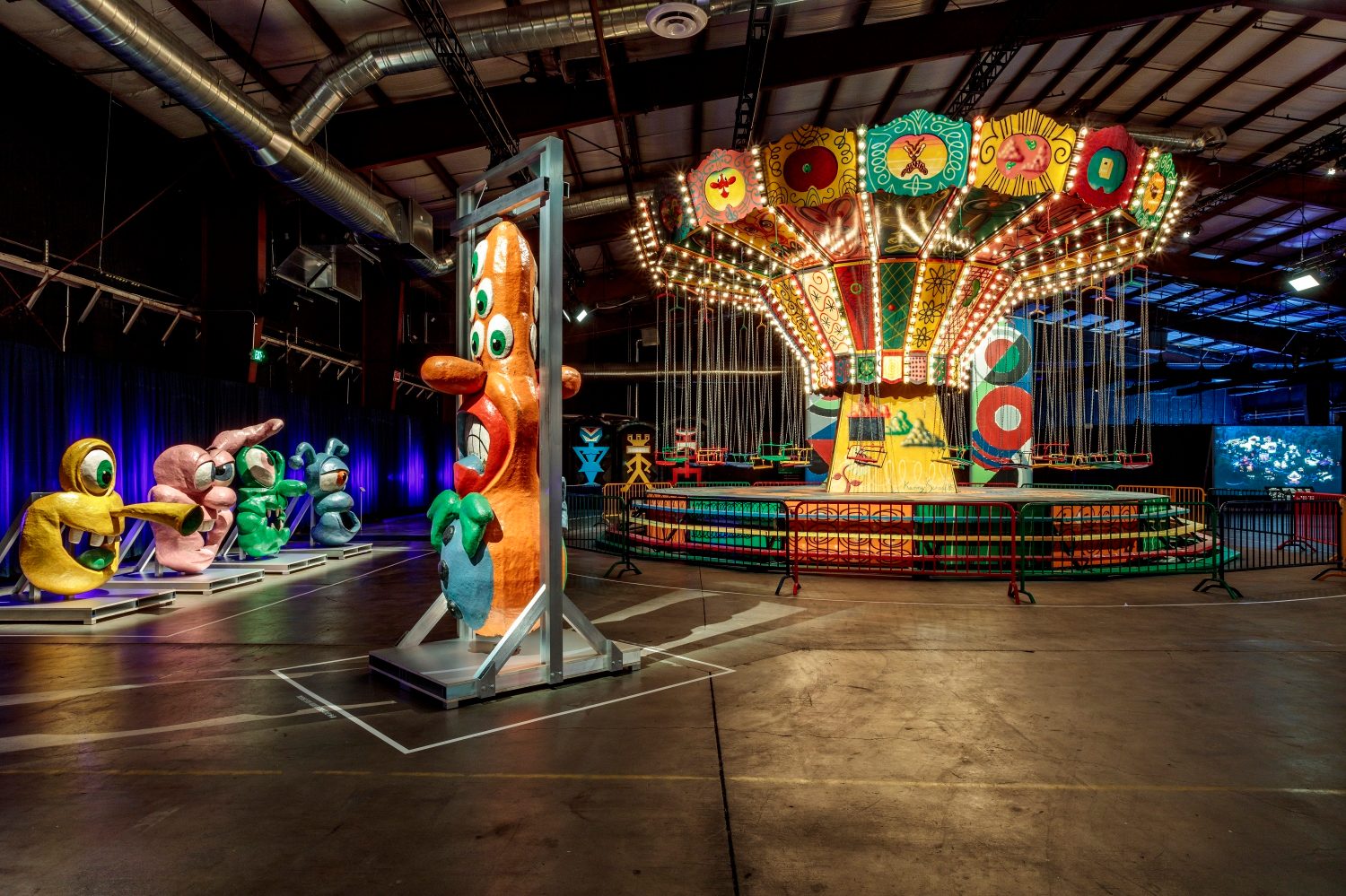 Kenny Scharf sculptures beside the illuminated swing ride